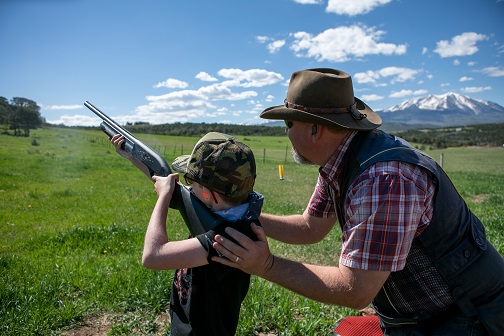 Youth shooting shotgun with instructor